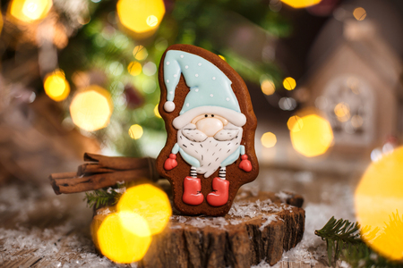 Holiday traditional food bakery. Gingerbread little fairytale gnome in cozy decoration with garland lights.の写真素材