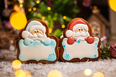 Holiday traditional food bakery. Two gingerbread of santa claus with copy space in cozy warm decoration with garland lights.の写真素材