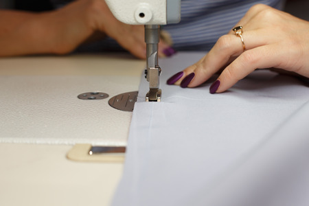 View from above on hands of female tailor working on sewing machine.  dress manufacturing industry.の写真素材