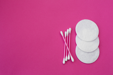 top view on pink cotton buds with white heads and white round cotton disks laid out on a pink background.の写真素材