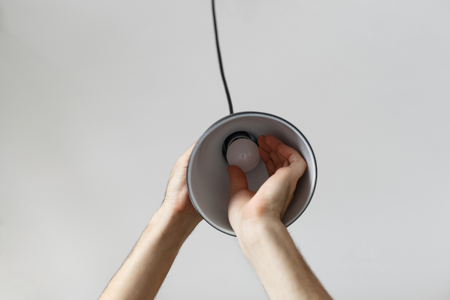 Changing the bulb for led bulb in floor lamp in black colour. On light gray background.の写真素材