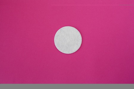 top view on white round cotton disks laid out on a pink background.の写真素材