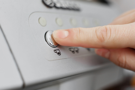 finger presses the round button under which a cup of coffee is drawn. Click to make coffee.の写真素材