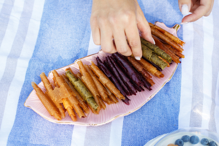 top view woman hands take pastillum roll from tray. Summer picnic.