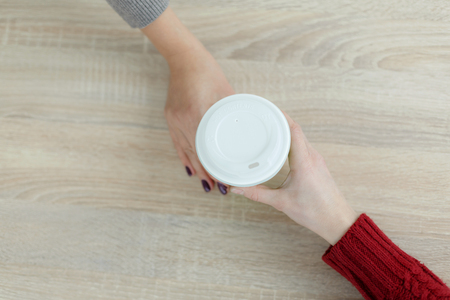 Barista in apron is giving hot coffee in green takeaway paper cup to customer. Coffee take away at cafe shop.の写真素材