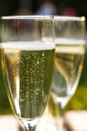 Glasses with champagne on green blurred background. Outdoors picnic weekends.の写真素材