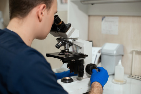 Laboratory assistant looking through microscope. Make research in laboratory. Science and medicine...
