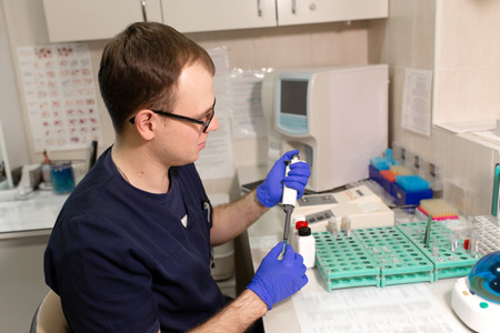 laboratory assistant analyzing a blood sample using micropipette.