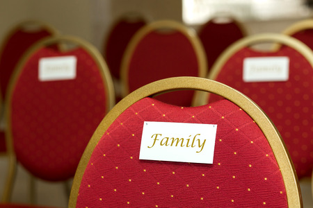 Seating chairs for guests at a wedding ceremony in the festive hall. Chairs upholstered in red cloth nameplate family.の写真素材