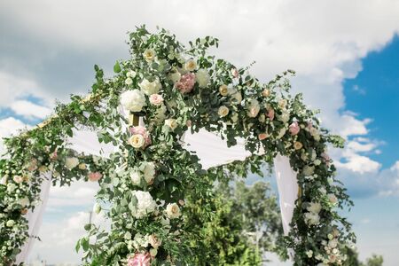 A festive chuppah decorated with fresh beautiful flowers for an outdoor wedding ceremony.の写真素材