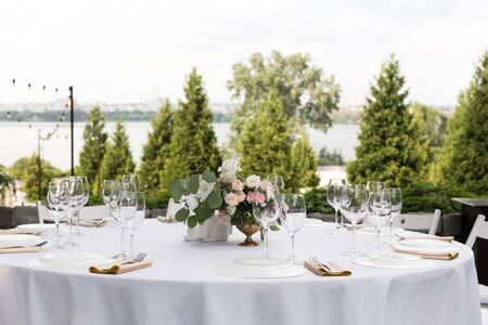 Wedding table setting decorated with fresh flowers in a brass vase. Wedding floristry. Banquet table...