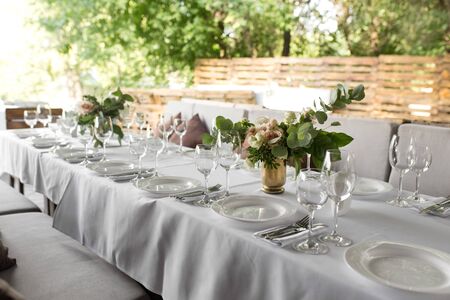 Wedding table setting decorated with fresh flowers in a brass vase. Wedding floristry. Banquet table...