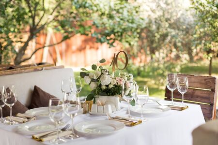 Wedding table setting decorated with fresh flowers in a brass vase. Wedding floristry. Banquet table...