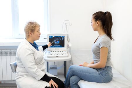 The doctor explains to the patient girl the results of her ultrasound examination, showing problem...