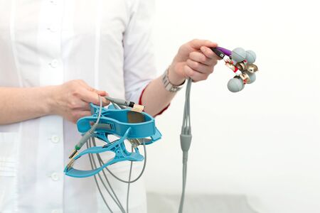 The cardiologist holds the electrocardiograph sensors in his hands before connecting them to the...