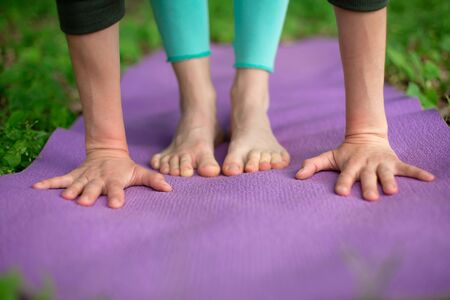 Thin brunette girl plays sports and performs yoga poses in a summer park. Green forest on the...