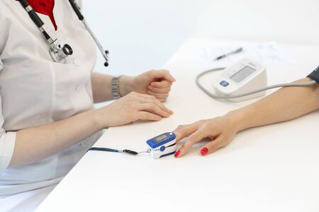 The doctor puts on the sensor measuring the pulse and oxygen in the blood on the patient's finger.