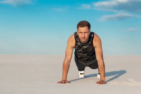 Fitness man doing exercises in sand desert. Sport concept.