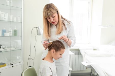 doctor trichologist examines the hair of a little girl patient in his office.の写真素材
