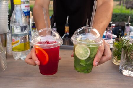 The bartender puts ready-made refreshing drinks on the bar. Street food festival.