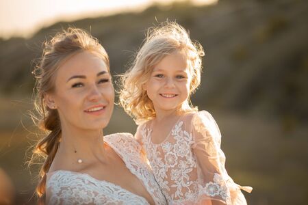 Portrait of a beautiful young mom holds her beloved daughter in her arms. Parental love, little princess.の写真素材