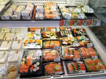 Sets of chilled sushi and fresh fish in plastic boxes in a supermarket refrigerator.のeditorial素材