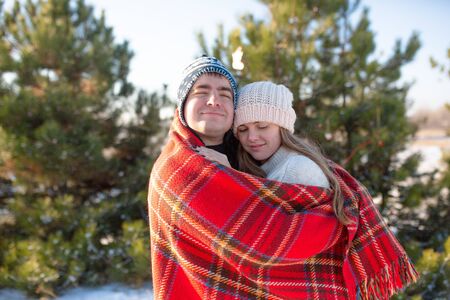 Winter walk through the woods. The guy in the red plaid blanket wraps the girl up so she gets warm.の写真素材