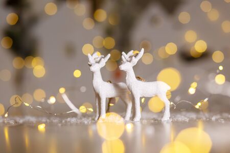 Decorative Christmas-themed figurines. Christmas deer. Christmas tree decoration. Festive decor, warm bokeh lightsの写真素材