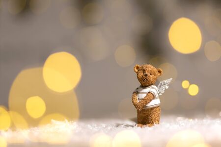 Decorative figurines of a Christmas theme. Figurine of a cute bear with angel wings. Festive decor, warm bokeh lights.の写真素材