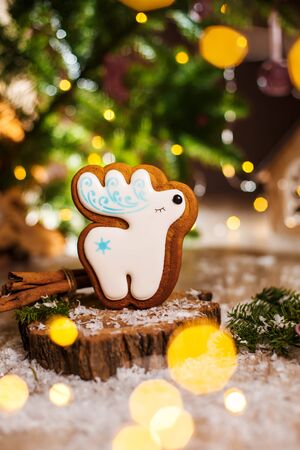 Holiday traditional food bakery. Gingerbread white christmas deer in cozy warm decoration with garland lights.の写真素材