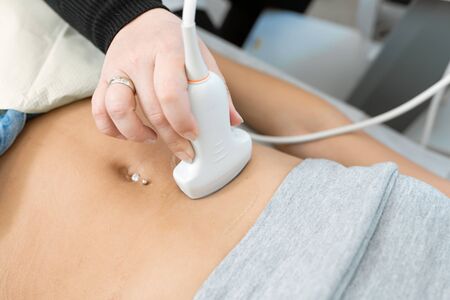 Close-up doctor conducts ultrasound diagnostics of the patients abdomen and internal organs.