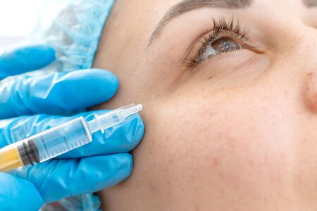 Close-up, beautician makes beauty injections into the skin of a young beautiful girl. Facial care...