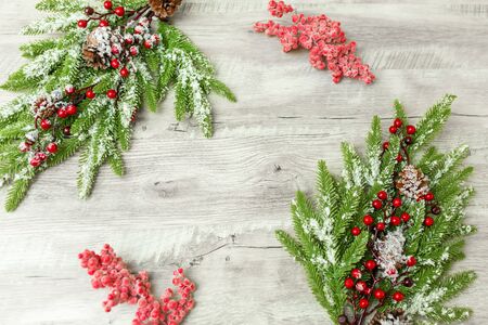 Christmas decorations. spruce branch with red berries lie on a light wooden background.の写真素材
