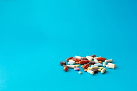 A scattered handful of colored pills on a blue background. Medical concept.