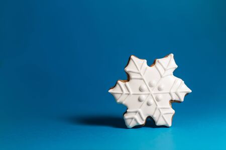 gingerbread cookie of snowflake on blue background. Traditional Christmas food. Christmas and New Year holiday concept. Copyspace.の写真素材