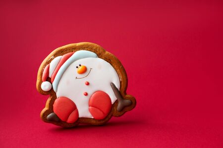 gingerbread cookie of round snowman on red background. Traditional Christmas food. Christmas and New Year holiday conceptの写真素材