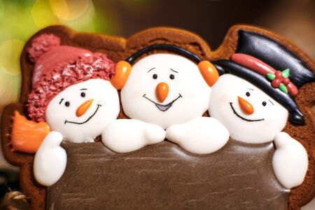Holiday traditional food bakery. Gingerbread three fun snowmans in cozy warm decoration with garland...