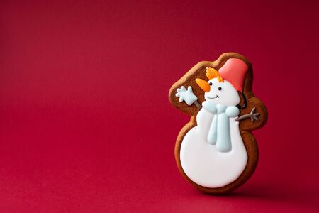 gingerbread cookie of cute snowman on red background. Traditional Christmas food. Christmas and New Year holiday conceptの写真素材