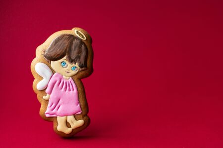 gingerbread cookie of little cute angels on red background. Traditional Christmas food. Christmas and New Year holiday conceptの写真素材
