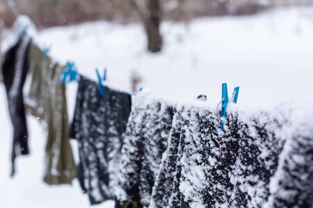Winter. Clothes are drying on the street. Clothes covered with snow dries on a tightened rope