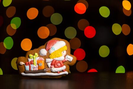 gingerbread cookie of little postman  Santa over defocused colored lights of garland. Traditional Christmas food. Christmas and New Year holiday conceptの写真素材