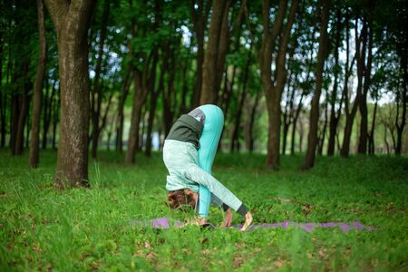 A young sports girl practices yoga in a quit green summer forest, yoga assans posture. Meditation and unity with nature.の写真素材