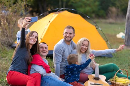 Selfie of friends on nature. Friends are resting near the lake. Great fun company. Big family gathered together on vacation. Children and parents on a picnic in the summer forestの写真素材