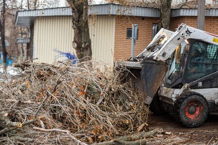 Urban emergency service removes a fallen tree on a road with special equipment traktor