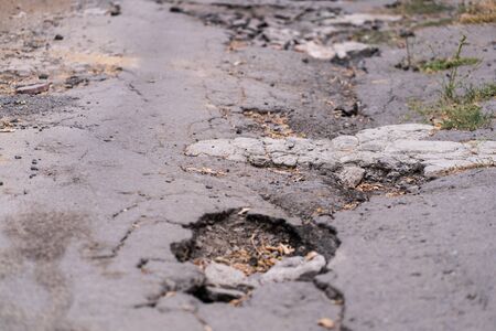 asphalt road destroyed by holes and washed out by water.の写真素材