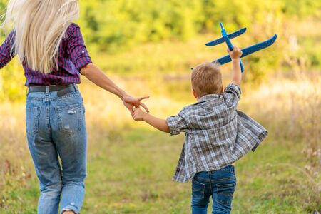 Little boy playing with toy airplane with his young mom outdoors at sunset. Happy Kid is playing in park outdoorsの写真素材