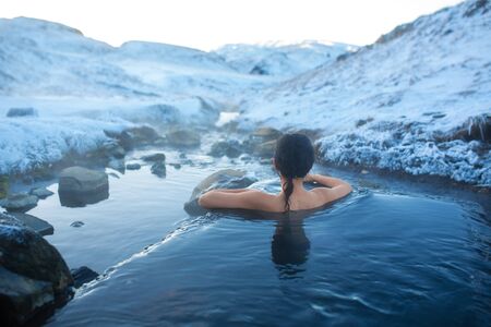 The girl bathes in a hot spring in the open air with a gorgeous view of the snowy mountains. Incredible iceland in winter.の写真素材