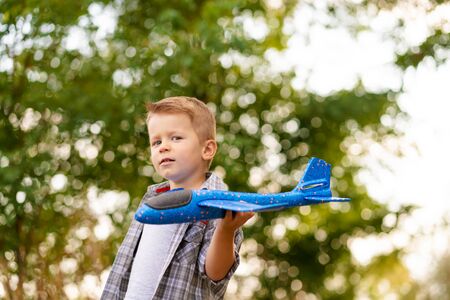 Young boy play with toy airplaine in hands. Happy Kid is playing in park outdoorsの写真素材