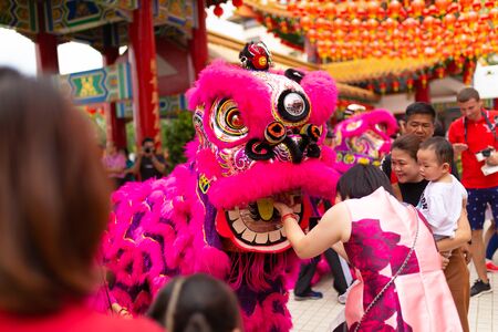 Chinese New Year celebration in a Chinese temple. A Chinese dragon dances and distributes sweets and...