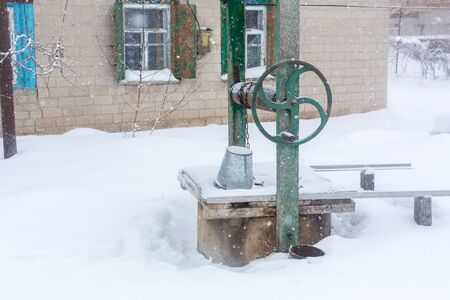 Winter. An old water well is covered in snowの写真素材